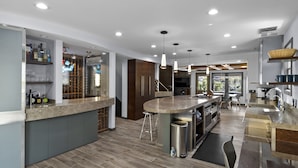 A modern kitchen with a central island, bar area, and built-in wine storage.