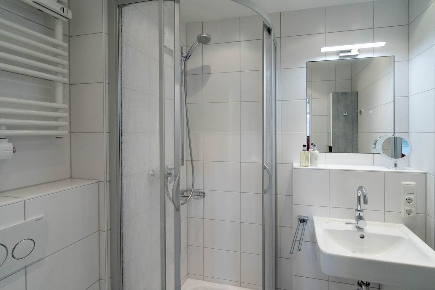 A modern bathroom with a glass-enclosed shower, a white sink, and a mirror above the sink.