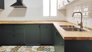 A modern kitchen with dark cabinets, a wooden countertop, a stainless steel sink, and a window providing natural light. - Sun Terrace Penthouse Living4malaga (Málaga)