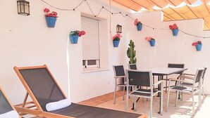A patio with a table and chairs, a lounge chair, and potted plants. - Sun Terrace Penthouse Living4malaga (Málaga)