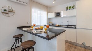 A modern kitchen with a central island, bar stools, a microwave, and a sink.