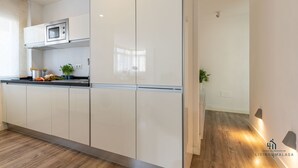 A modern kitchen with white cabinets, a microwave, and a plant on the counter.