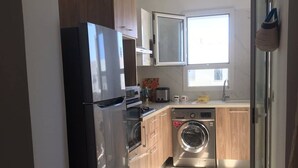 Une cuisine moderne équipée d’un réfrigérateur, d’un four, d’un four à micro-ondes et d’un lave-linge.