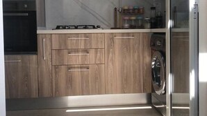 Une cuisine moderne avec des meubles en bois, un four encastré, une cuisinière, un four à micro-ondes et un lave-vaisselle.
