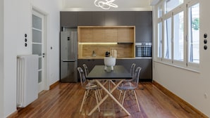 A modern kitchen with a central island, wooden flooring, and large windows. - 3Bdr Modern Design & Bright Interiors in Plaka (Athens)