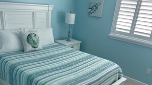A bedroom with a bed, nightstand, lamp, and artwork on the wall.