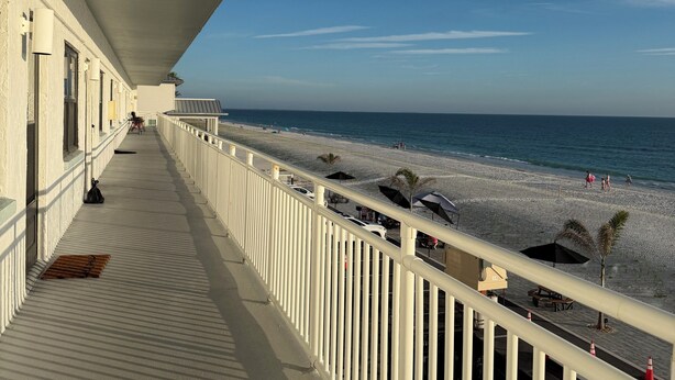 A balcony with a view of the beach and ocean.