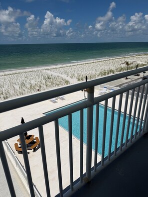 A poolside view with a beach and ocean in the background.