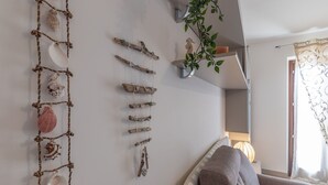 A living room with a sofa, a wall-mounted plant, and a decorative rope art piece. - Nice apartment for 4 people with WIFI, TV and patio, close to Porto Recanati (Loreto)