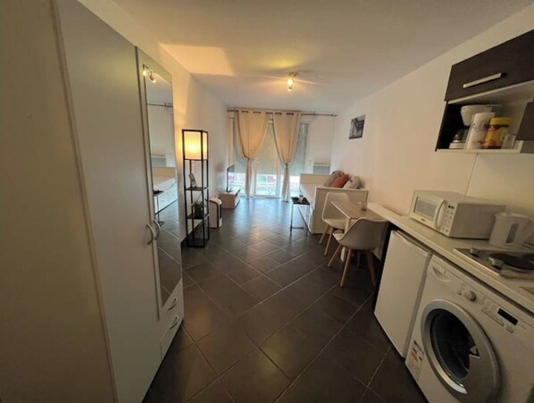 A modern kitchen with a washing machine, a microwave, and a dining area with a table and chairs.
