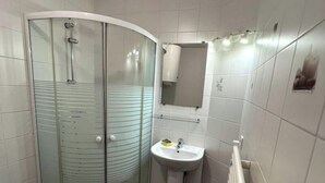 A small bathroom with a glass shower enclosure, a pedestal sink, and a towel rack. - Beau Studio Nice - Riquier (Nice)