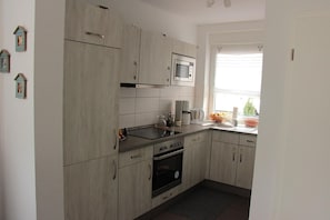 Una cocina moderna con gabinetes grises, un microondas, una estufa y un lavaplatos.