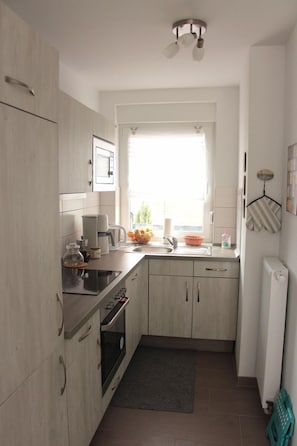 Uma cozinha compacta com forno embutido, cafeteira e pia.
