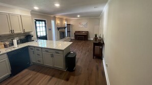 A spacious kitchen with a central island, wooden flooring, and a built-in fireplace.
