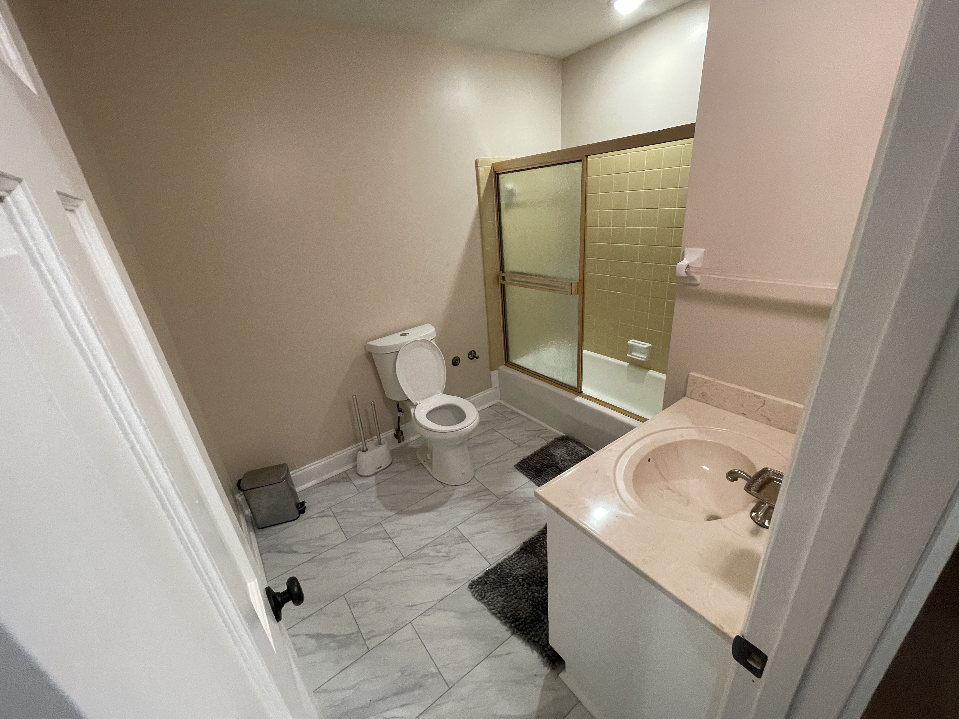 A bathroom with a toilet, shower, and sink.