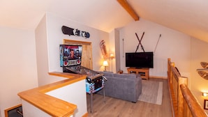 Una sala de estar con una consola de videojuegos, un televisor y un sofá.