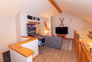 A living room with a gaming console, a television, and a couch. - Hideaway Down Canyon #110, End Unit close to June Mtn (June Lake)