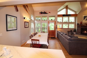 A spacious living area with a dining table, a gray sofa, and a fireplace. - Hideaway Down Canyon #110, End Unit close to June Mtn (June Lake)