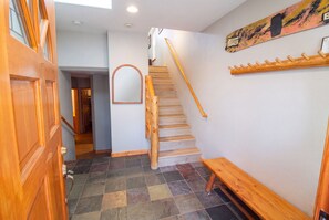Un escalier en bois avec une rampe, un miroir fixé au mur et un banc en bois.