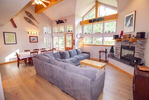A spacious living area with a sectional sofa, dining table, chairs, and a fireplace. - Hideaway Down Canyon #110, End Unit close to June Mtn (June Lake)