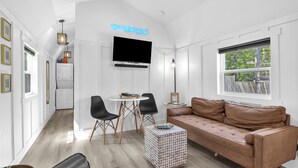 A modern living room with a brown leather sofa, a white coffee table, and a TV mounted on the wall.