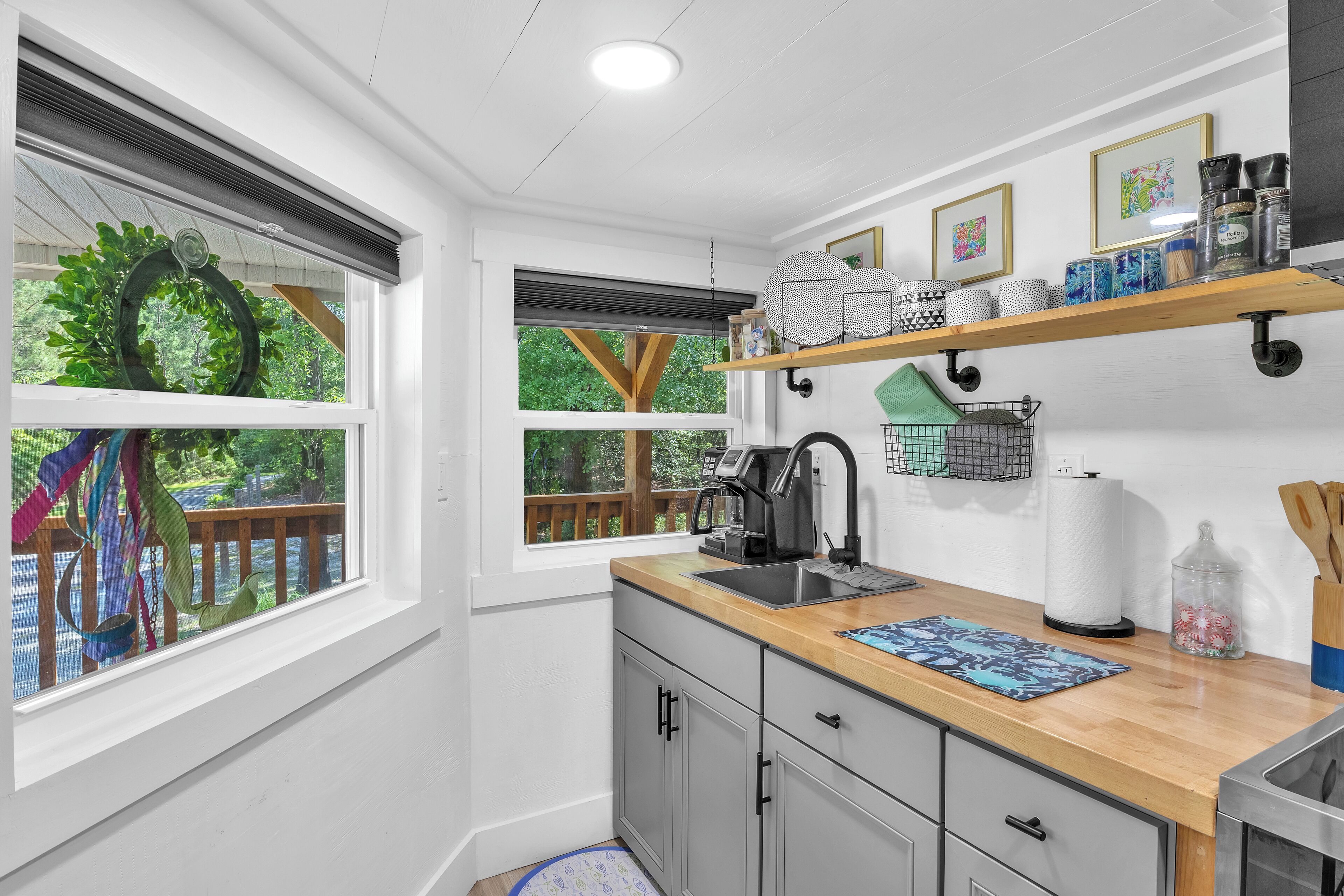 A kitchen with a wooden countertop, a sink, and a window overlooking a deck.