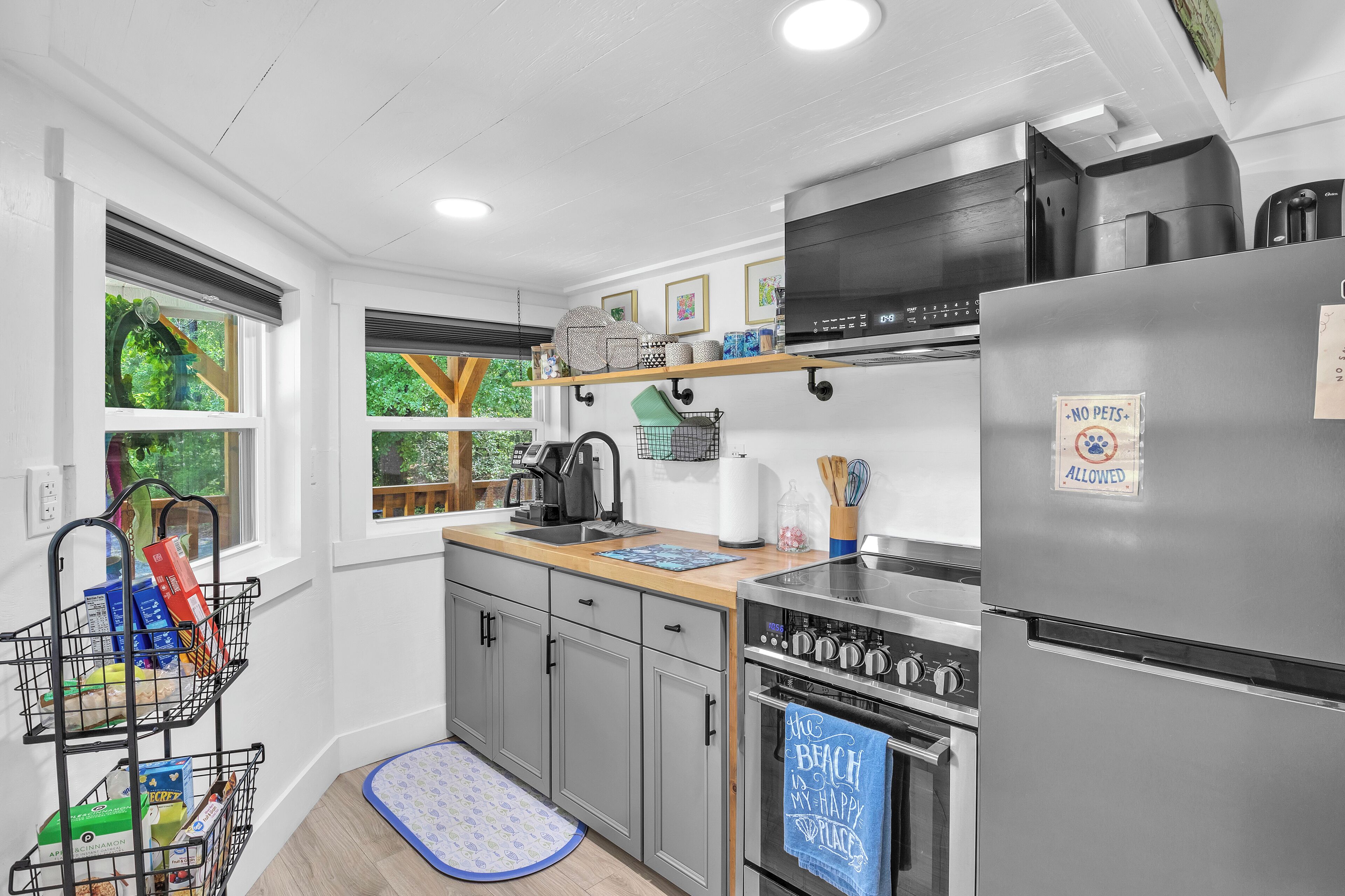 A modern kitchen with grey cabinets, a stainless steel refrigerator, and a built-in oven.