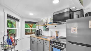 A modern kitchen with grey cabinets, a stainless steel refrigerator, and a built-in oven.