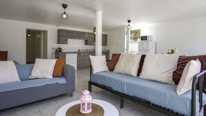 Un salon moderne avec deux canapés, une table basse et une cuisine en arrière-plan.