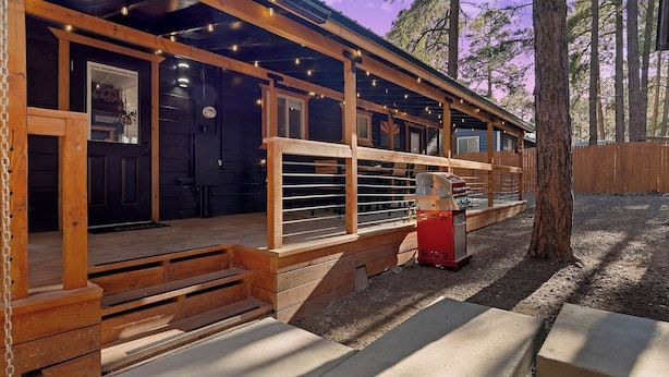 Eine rustikale Holzhütte mit Veranda, Grill und Holzlattenzaun.