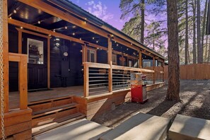 A rustic cabin with a porch, a grill, and a wooden fence. - Cool Retro White Mountain Cabin (Lakeside)