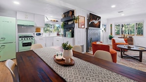 Eine moderne Küche mit einem grünen Herd, weißen Schränken und einem Essbereich mit einem Holztisch und orangefarbenen Stühlen.