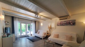 A modern living room with a sofa, a coffee table, and a television. There is a sliding glass door leading to an outdoor area. - MAGNIFICENT T2 58m2 air-conditioned PORT FREJUS 4/5 P in residential area, terrace, quiet and close to everything (Fréjus)