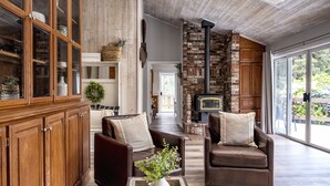 A spacious living room with a fireplace, leather sofas, and a wooden cabinet. - A luxurious vacation rental just minutes away from the beach! (Fort Bragg)