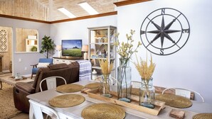 A modern living room with a large TV, a wooden ceiling, and a compass wall decoration. - A luxurious vacation rental just minutes away from the beach! (Fort Bragg)