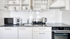 Une cuisine moderne avec des meubles blancs, un four à micro-ondes, une bouilloire et une cuisinière.