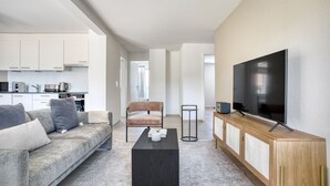 Un salon moderne comprenant un canapé, une table basse, un téléviseur et un coin cuisine.