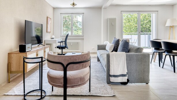 Un salon moderne avec un canapé, une table ronde et un téléviseur.