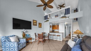 A spacious living area with a high ceiling, a dining set, a kitchen, and a staircase leading to an upper level. - Bright and Cheery Maui Vista 2 BR/2BA   MV2420 (Kihei)