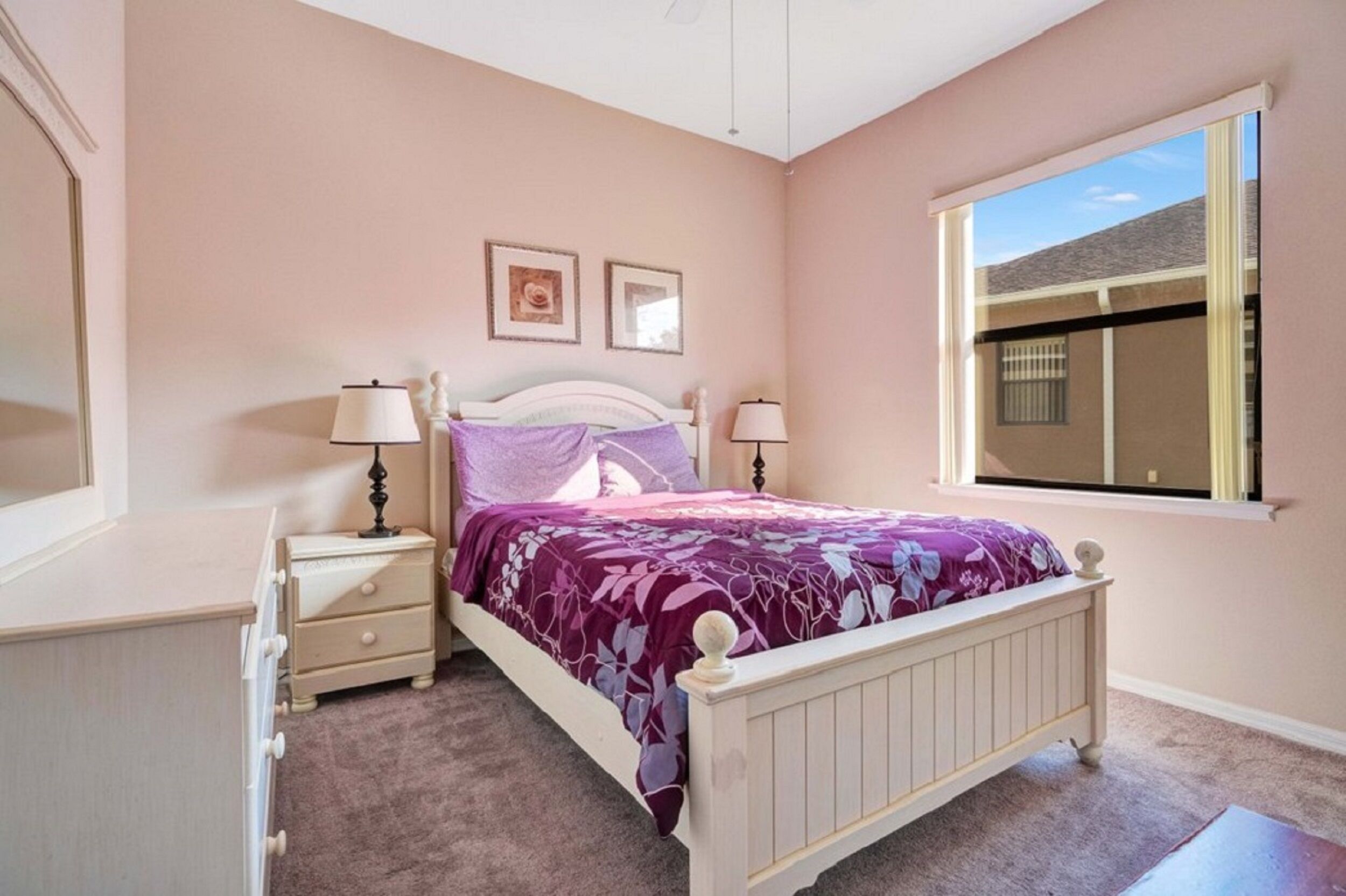 A bedroom with a bed, nightstands, a dresser, and a window.