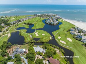 An aerial view of Ocean Point Golf Course with multiple water hazards, a central island, and a beachfront.