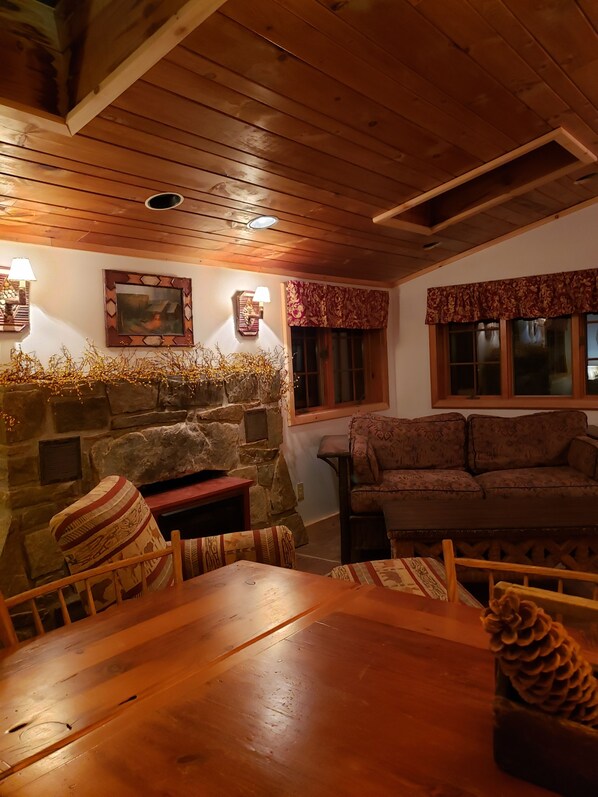 Un salon chaleureux avec une cheminée en pierre, un plafond en bois et un canapé.
