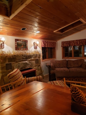 A cozy living room with a stone fireplace, wooden ceiling, and a sofa.