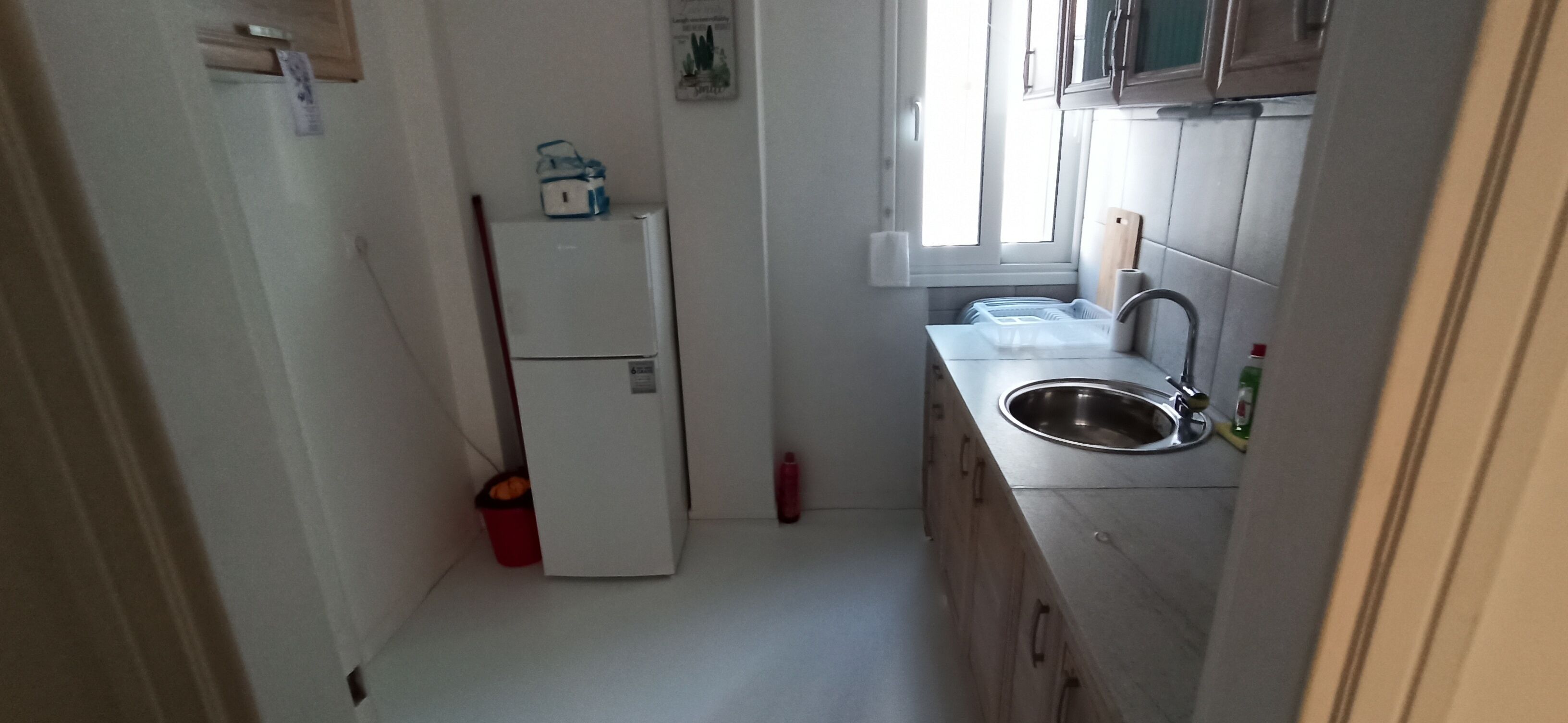 A compact kitchen with a refrigerator, sink, and cabinets.