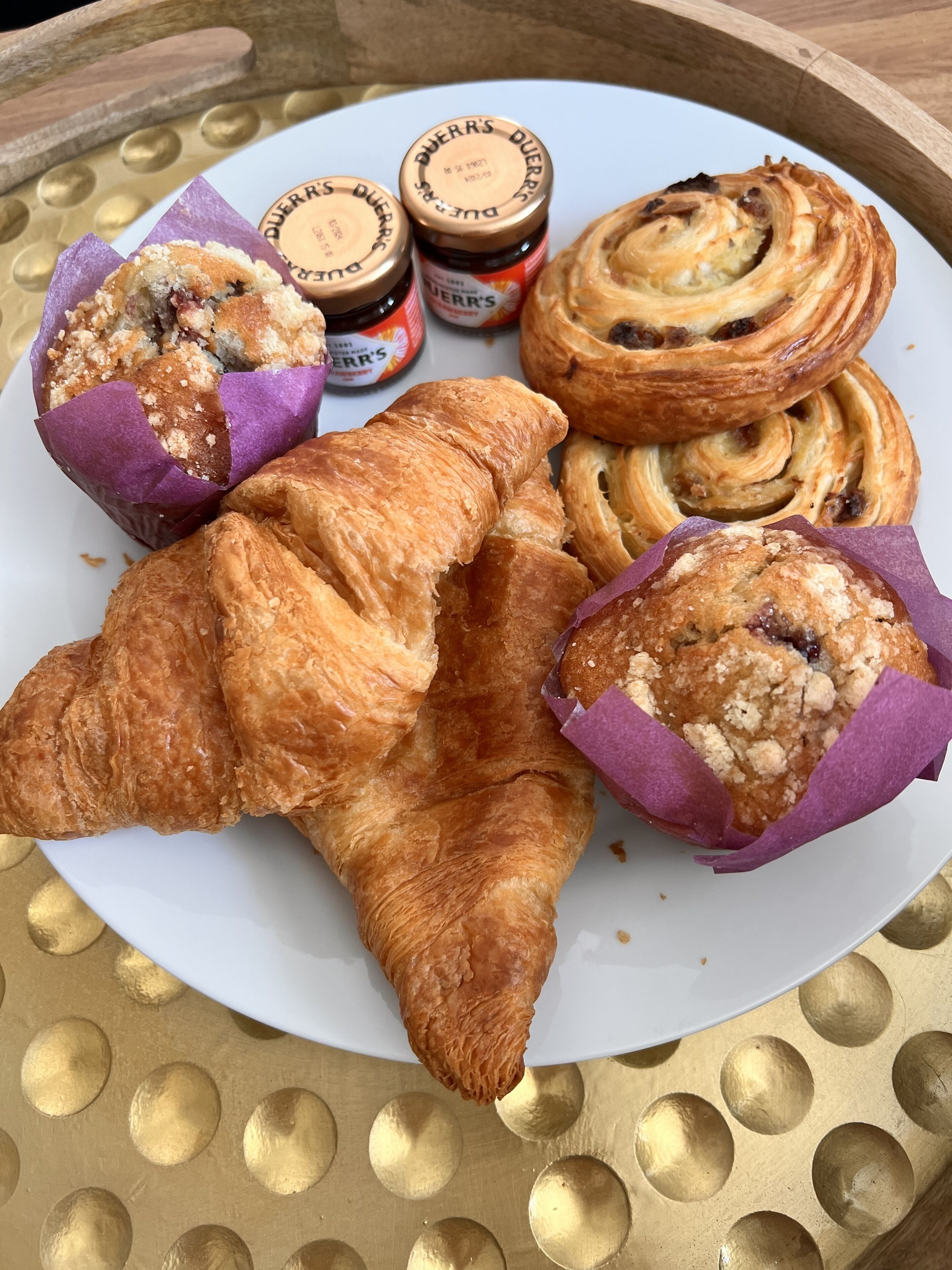 A plate with pastries and two jars of jam.