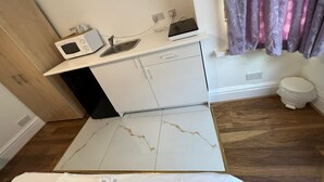 Kompakti keittiö, jossa on mikroaaltouuni, leivänpaahdin ja pieni pesuallas.