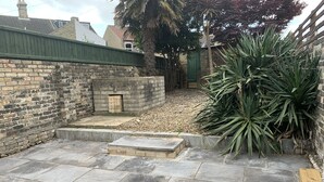 Un pati amb paviment de pedra, una paret de maó i una planta gran.