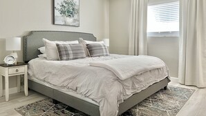 A bedroom with a bed, bedside tables, a ceiling fan, a window with curtains, and a wall-mounted artwork. - Downtown Gilbert *Pet-Friendly* Getaway (Gilbert)