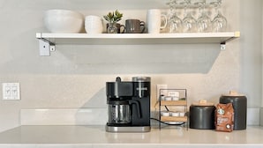 A kitchen with a coffee maker, a shelf with mugs and glasses, and a coffee bag. - Downtown Gilbert *Pet-Friendly* Getaway (Gilbert)