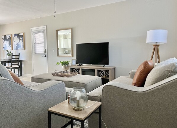 A living room with grey sofas, a TV, a lamp, and a small table with a vase.